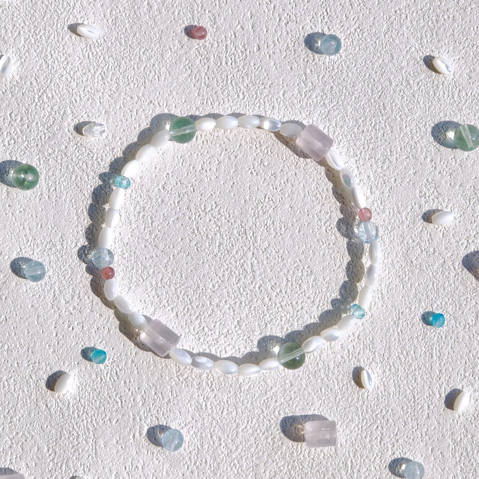 A pastel-coloured stone bracelet arranged with small stones on a textured surface